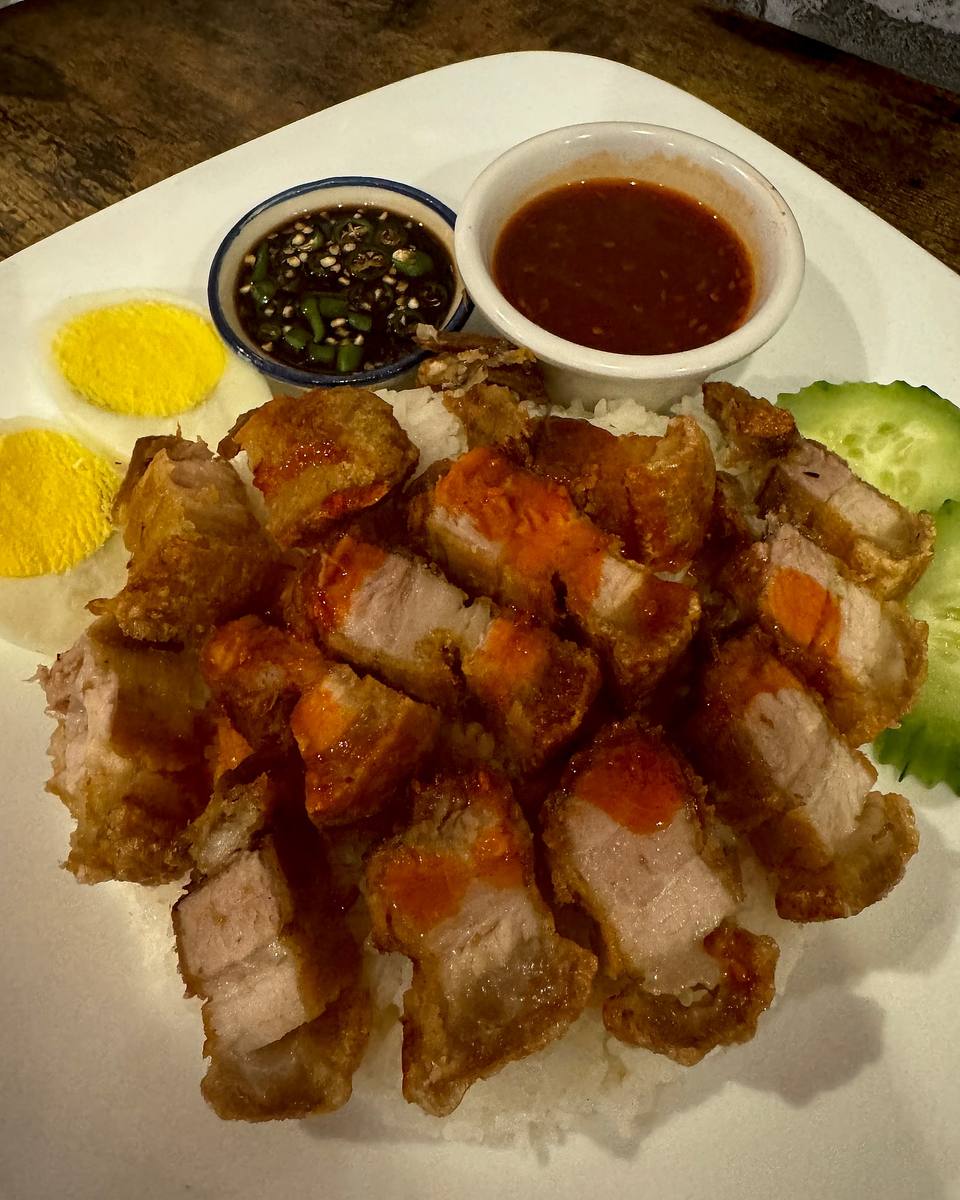 Crispy pork belly over rice with two dipping sauces.