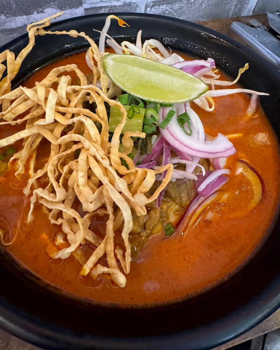 Khao Soi: chicken in a yellow curry noodle soup topped with crispy fried noodles, red onion, pickled greens and lime.